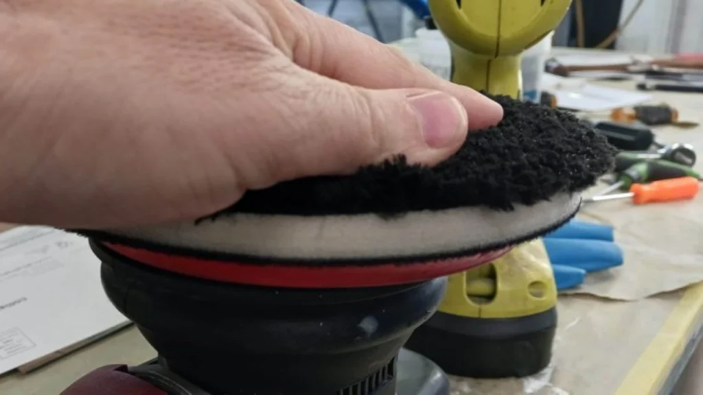 Professional detailer performing paint correction on a luxury vehicle using a dual-action polisher
