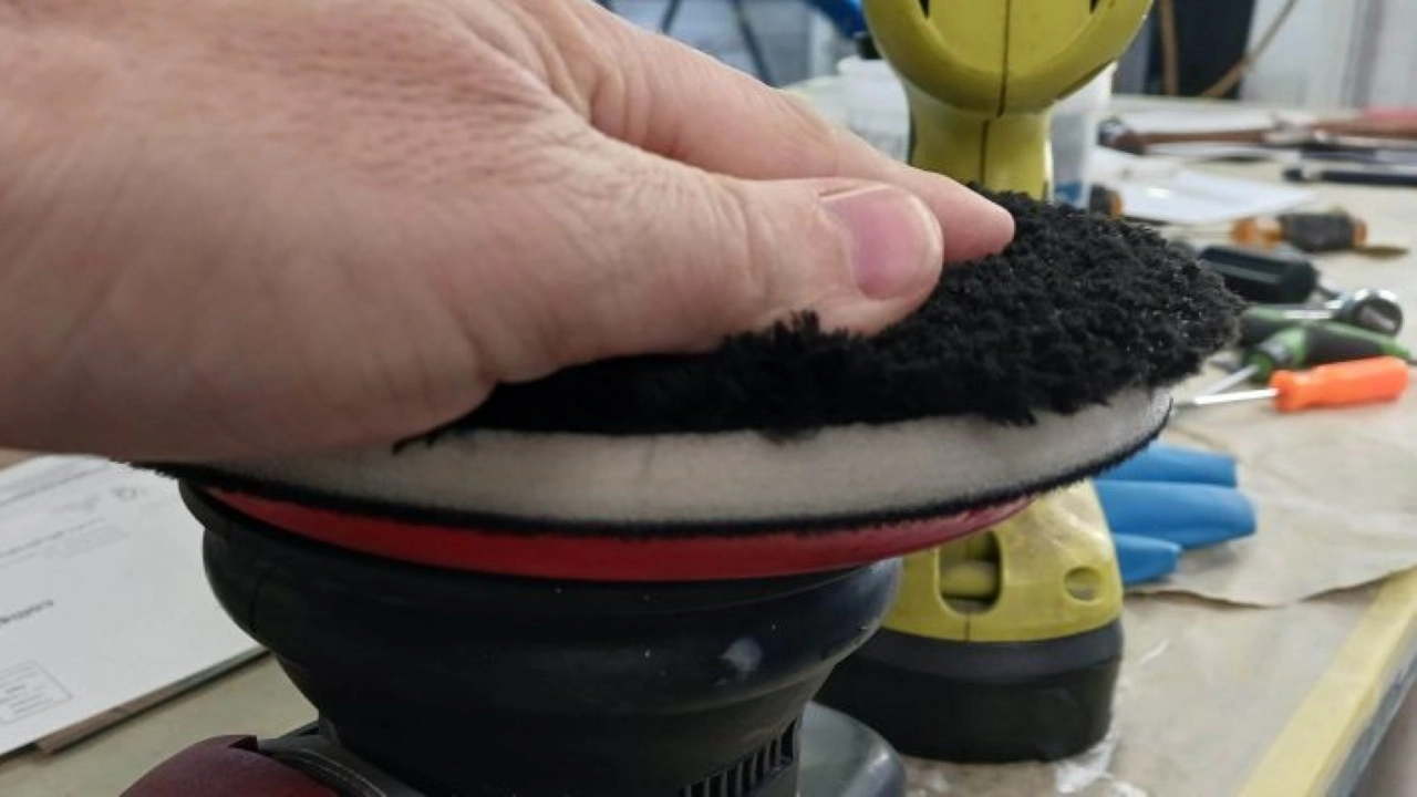 Professional detailer performing paint correction on a luxury vehicle using a dual-action polisher