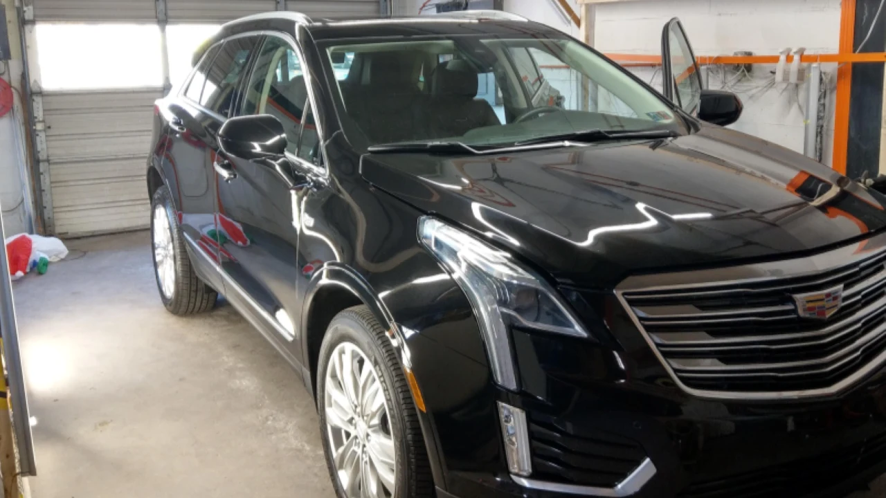 Black Cadillac SUV under shop lights before paint correction begins