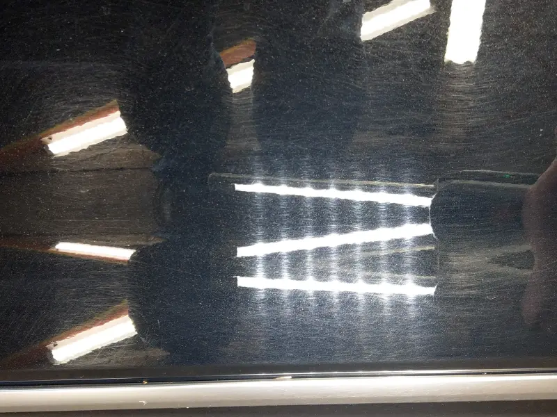 Closeup of Cadillac passenger door with heavy swirl marks before correction.