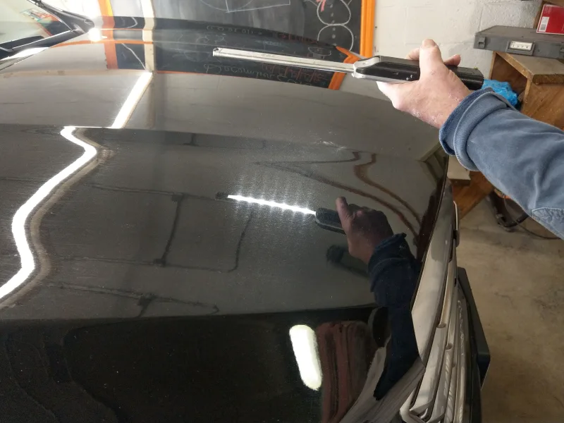 Cadillac hood with swirl marks highlighted by light wand during inspection