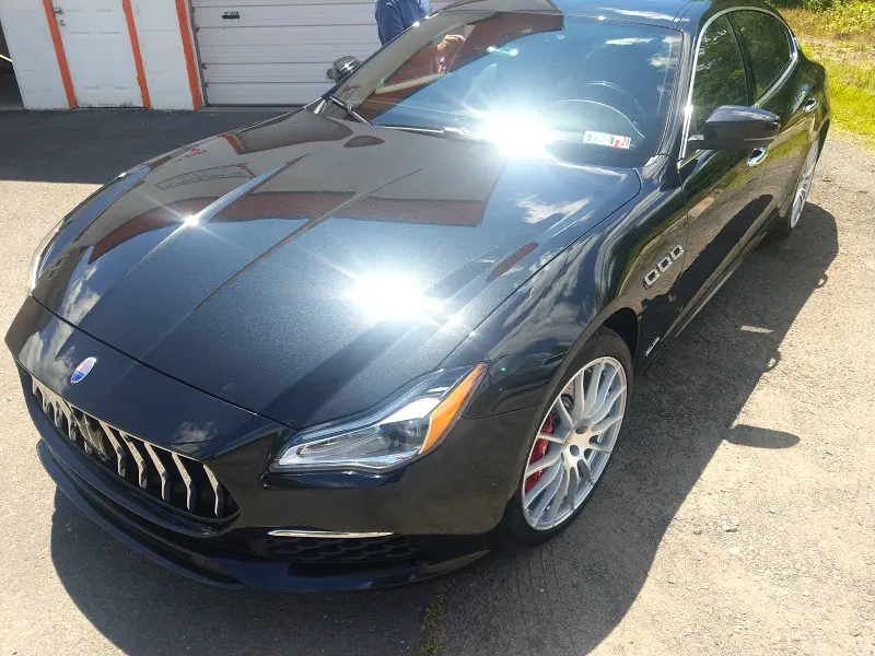 Dark blue Maserati right profile — sun reflection showing flawless ceramic coating
