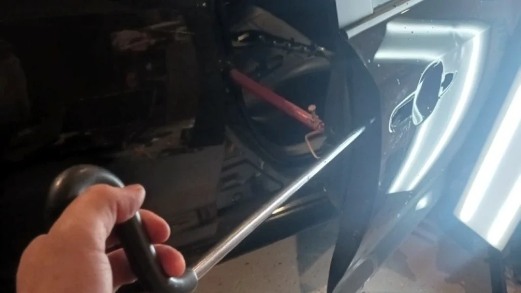 worker holding a tool showing access into a door. this shows How Does Paintless Dent Repair Work?