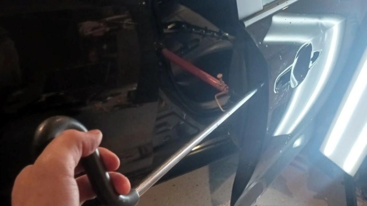 worker holding a tool showing access into a door. this shows How Does Paintless Dent Repair Work?