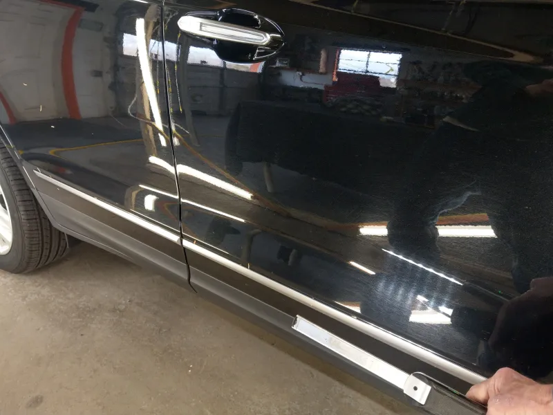 Passenger front door of Cadillac showing swirl marks under light wand