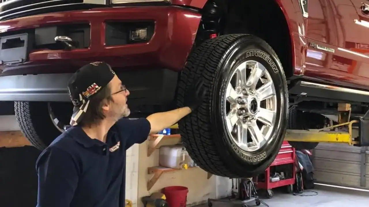 Ceramic coating technician completing a high‑gloss finish on a lifted Ford F250 in a controlled shop environment.