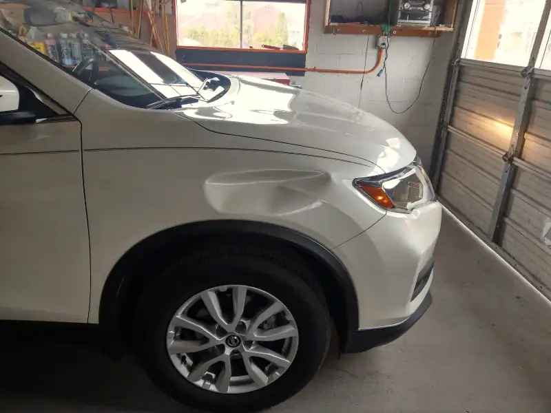 Before‑repair photo showing a fender dent suitable for paintless dent repair.