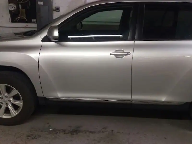 Refinished vehicle door panel shown for paintless dent repair service.