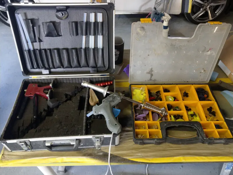 Glue pulling kit used during a paintless dent repair spotlight, showing the tools required for non‑invasive dent removal.