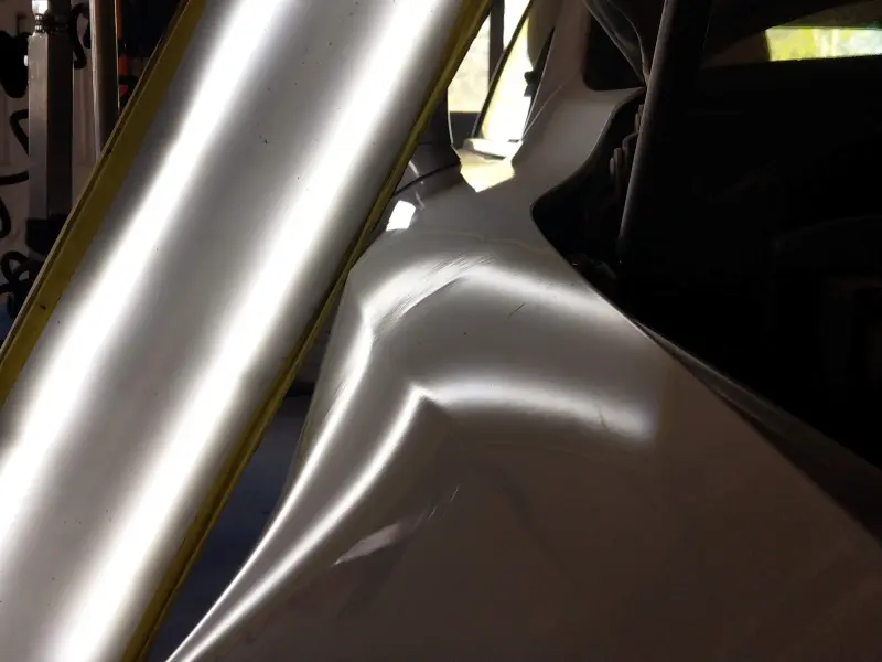Mid‑repair progress image from a paintless dent repair spotlight, showing the partially corrected Lexus fender kink as tension is gradually released from the panel.